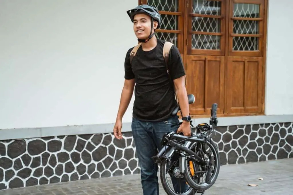 man carrying a folding bike